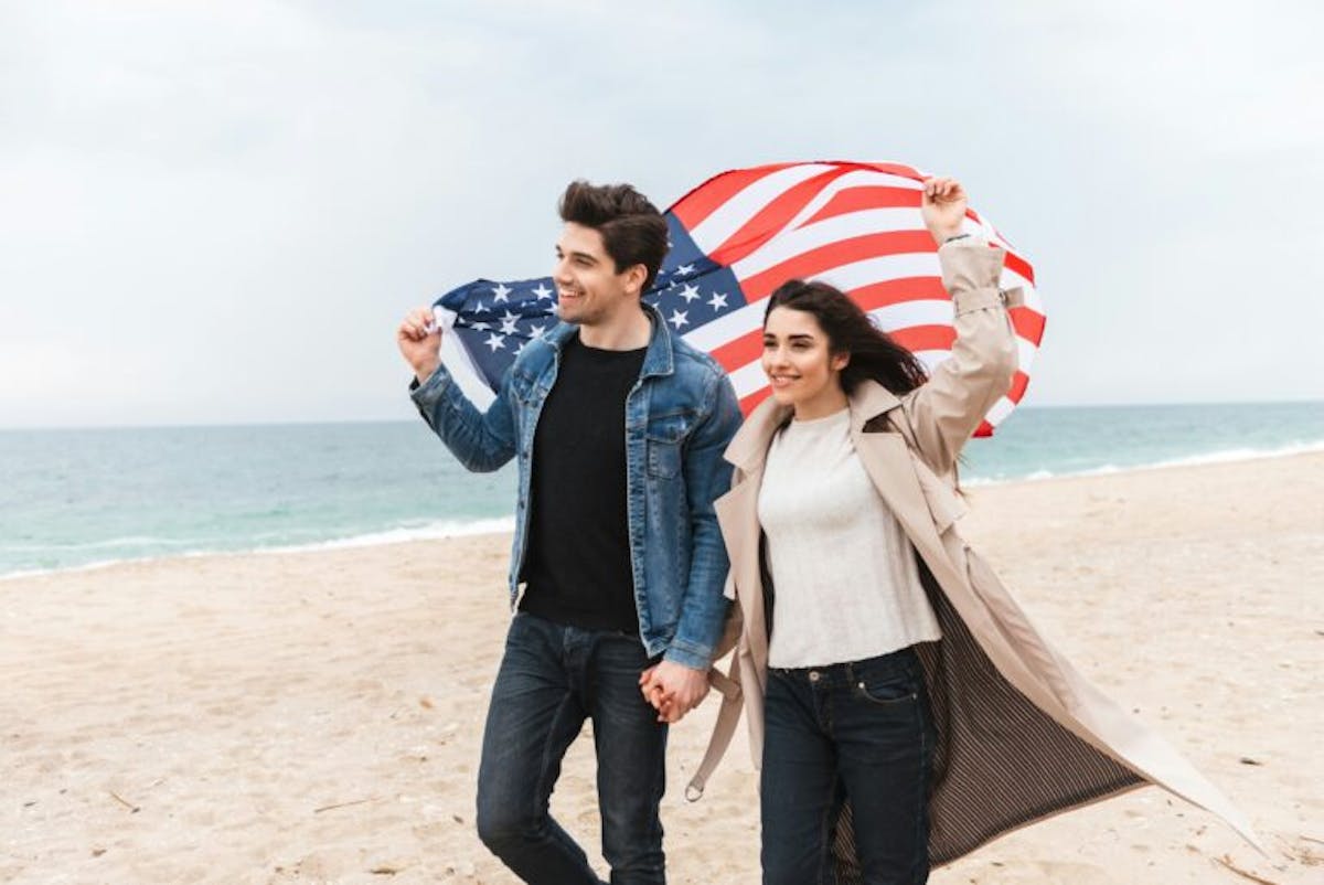 Happy couple on the beach holding an American flag